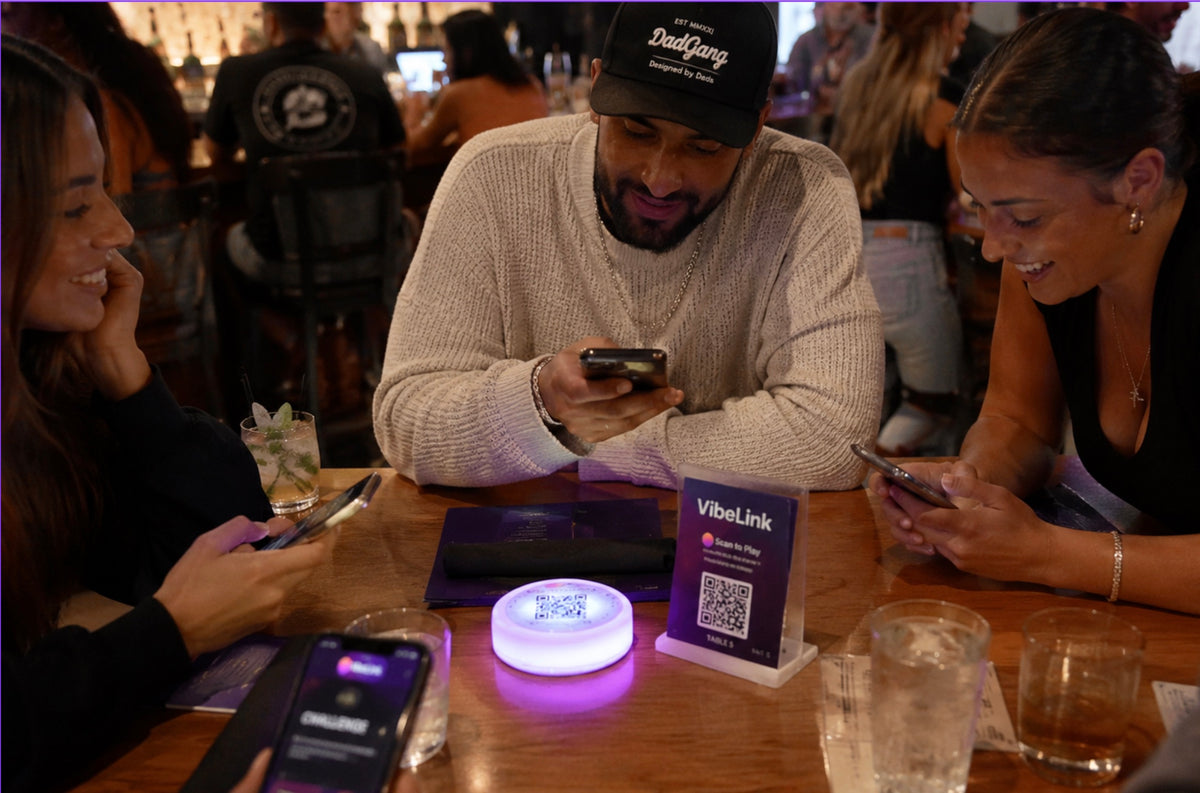 Guests connecting around a VibeLink light and QR stand
